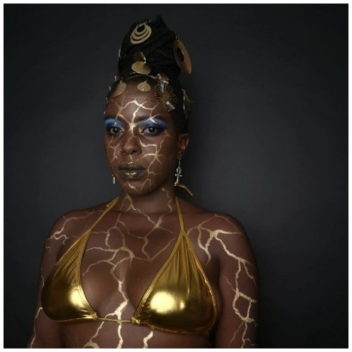 Chanje Kunda looks thoughtfully off camera with gold paint on her face in the style of Kiinstsugi, which imitates gold cracks