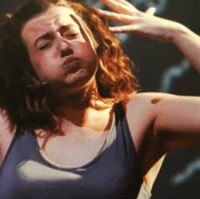A photo of a woman in a blue vest top making a dramatic gesture