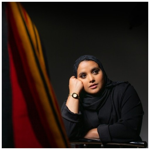 Yemeni-Scouse poet, Amina Atiq wearing a black hijab and leaning against her arm thoughtfully