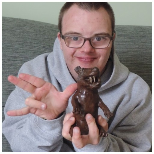 Dominic G wearing a grey hoodie and posing with a weasel sculpture