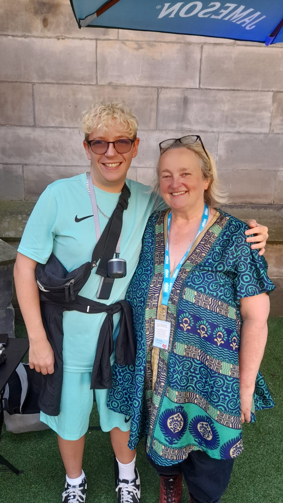 Denise stands outside a building with her arm around Anthony Gough