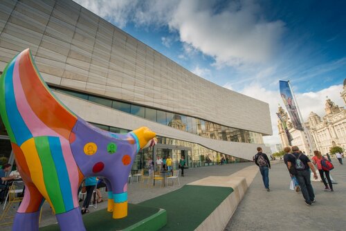 An image taken outside the museum of Liverpool including a colourful Superlambanana sculpture and passersby