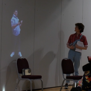 A young performer stood opposite a BSL interpreter projected on the wall