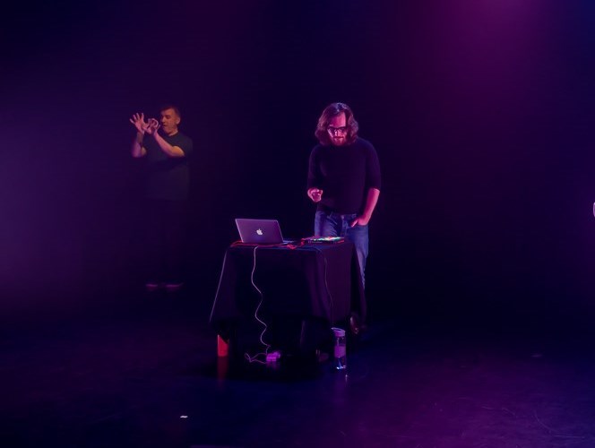 Person with long hair onstage alongside a BSL interpreter