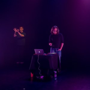 Person with long hair onstage alongside a BSL interpreter