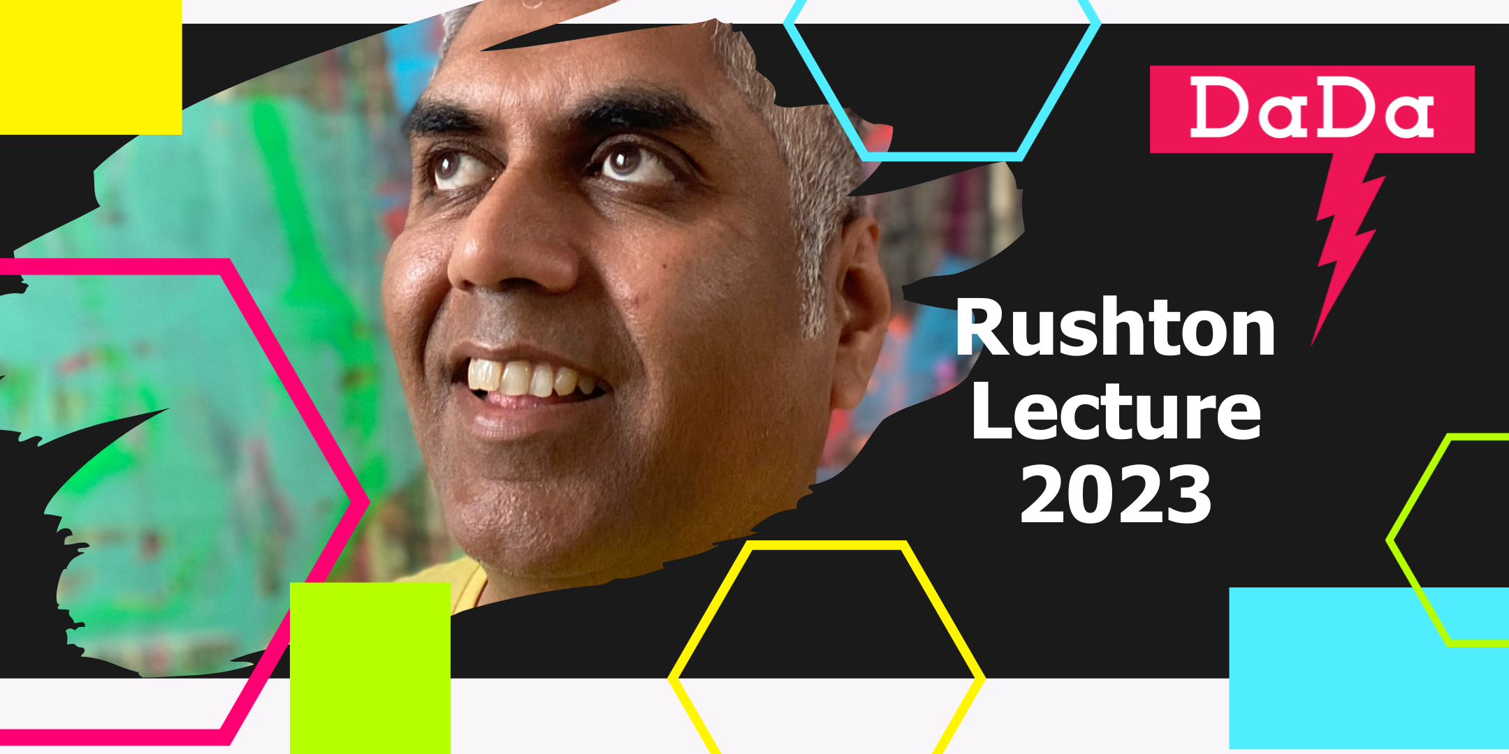 Headshot of Ashok Mistry, looking upwards and smiling. Ashok has grey short hair and is wearing a yellow t-shirt. Behind is colourful abstract art