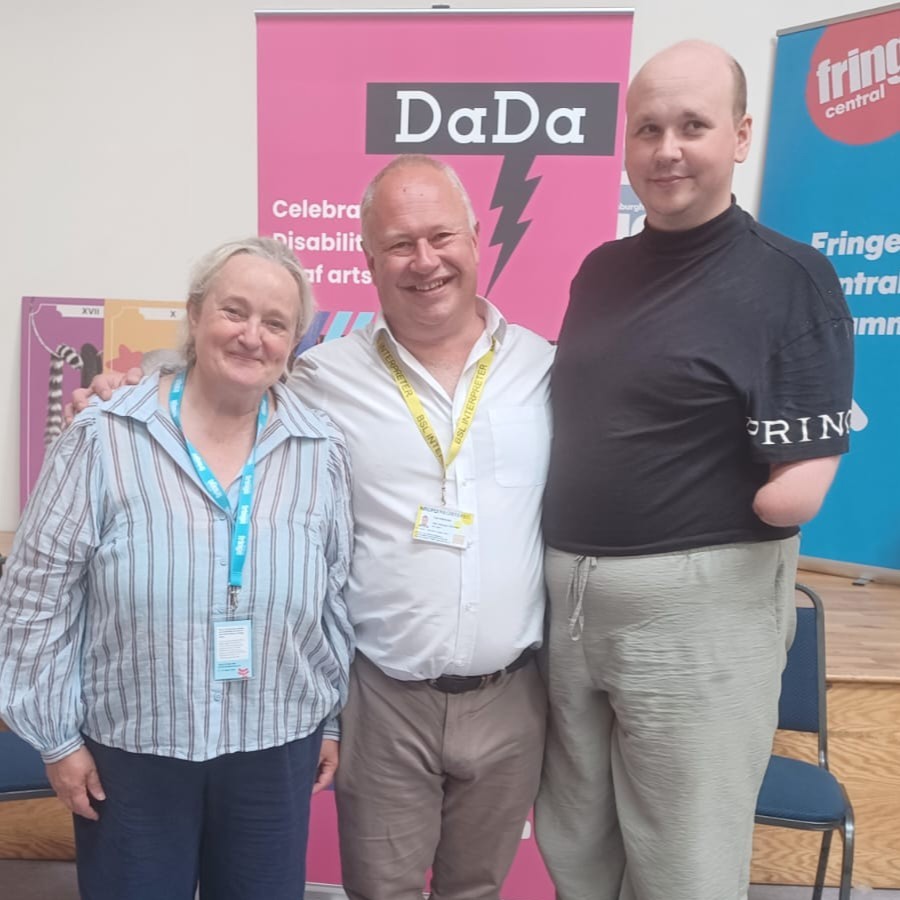 Denise and Ed from team DaDa stand with BSL Paul in front of DaDa pop up banner in Edinburgh 