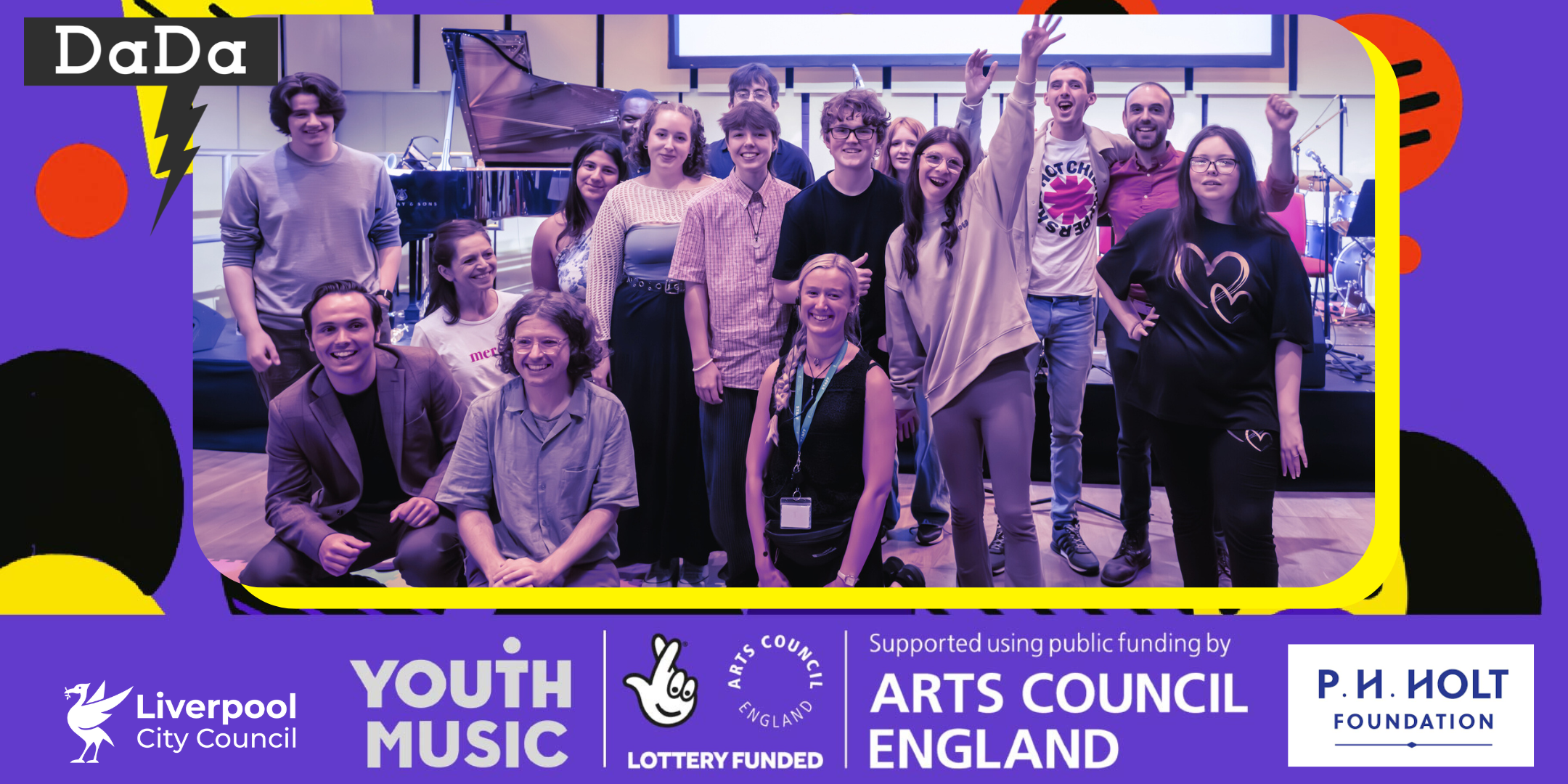 A group of young musicians are gathered together in front of a stage. They are smiling and celebrating.