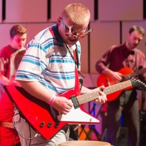 A young man onstage playing an electric guitar