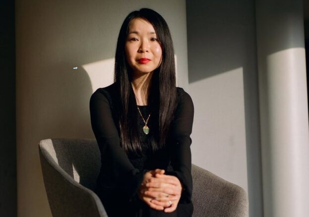 A photo of Jennifer Lee Tsai, an Asian woman wearing black, sat with her hands clasped on her knee.