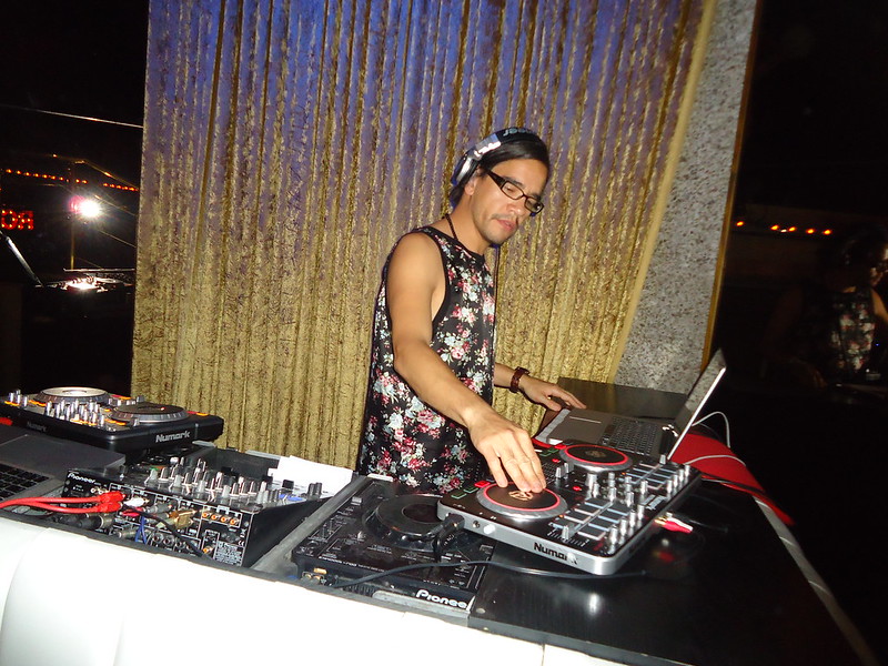 A DJ using DJ decks in front of a sparkly curtain