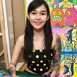 An Indonesian woman with Javanese heritage with long black hair, tattoos on both her sleeves and a piercing under her lip