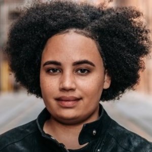 Woman of mixed Malawian and English heritage stood outside in a street smiling slightly