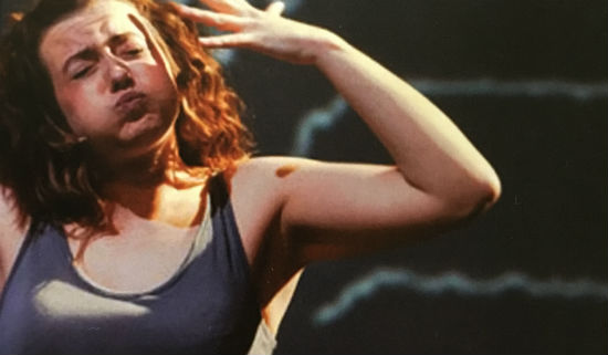 A photo of a woman in a blue vest top making a dramatic gesture