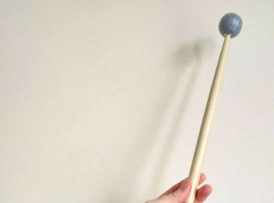 A photo of a hand holding a wooden drum stick