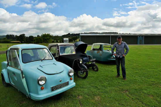 A photo of Simon standing in front of four Invalid Carriages of different ages parked in a field.