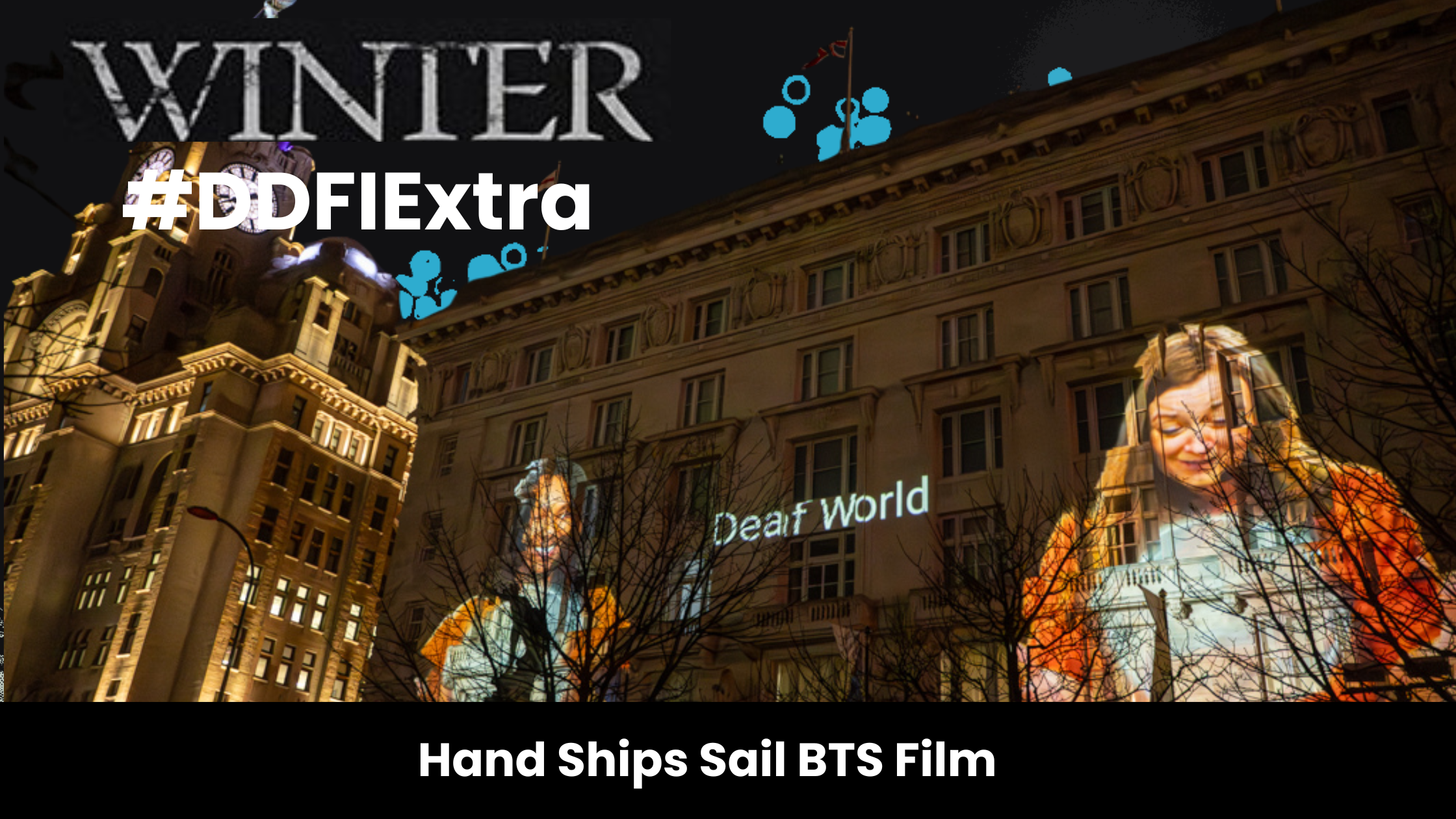 Two women gesturing in BSL have the words 'Deaf World' between them. They are projected in film onto the Cunard Building in Liverpool