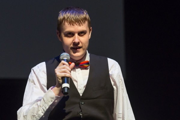 Young man wearing suit with a microphone on stage