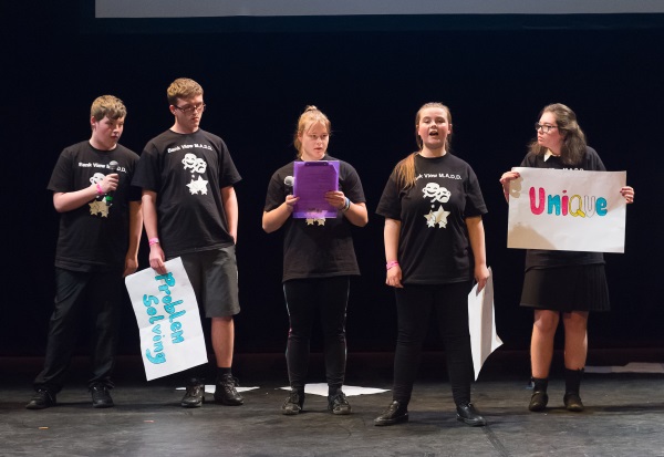 A group of young people on stage with microphones and signs