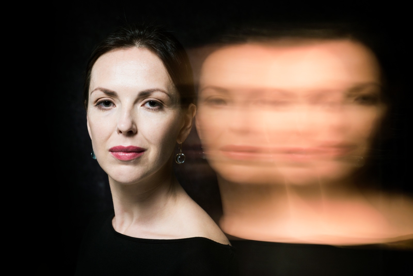 A woman with dark hair against a black background