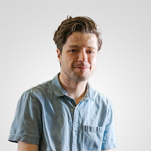 A photo of a young man wearing a light blue short sleeved shirt against a white background