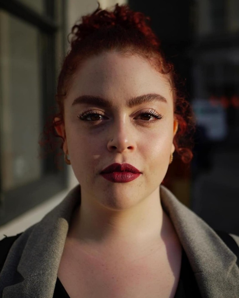 A woman with dark hair and red lipstick facing the camera 